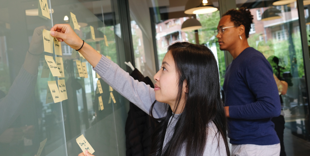 man and woman sticking notes to a board