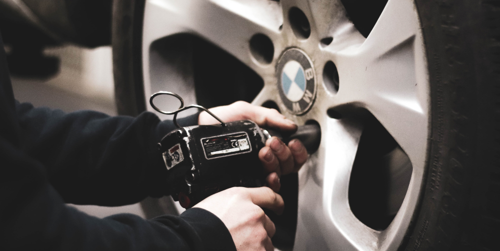 man in black jacket fixing BMW tire