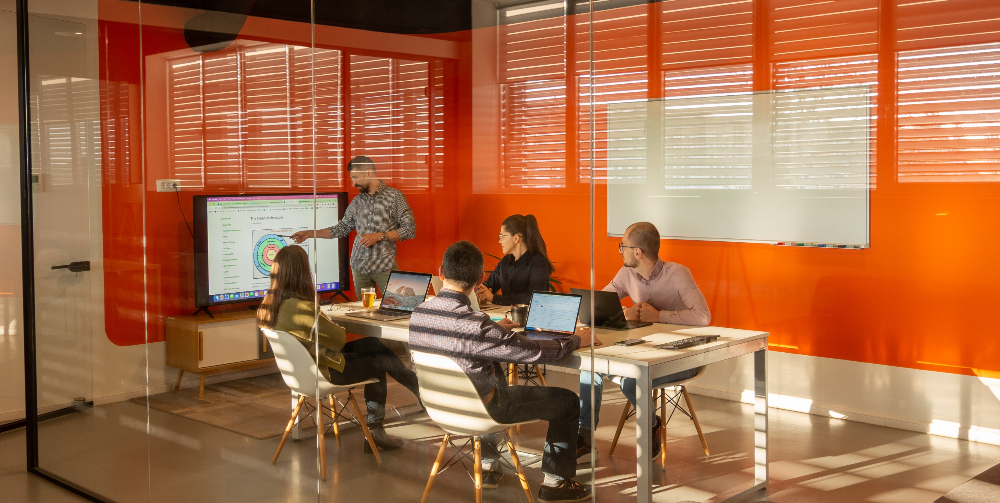 person presenting to team in orange room