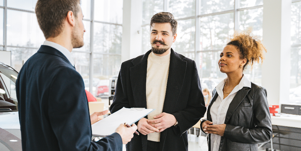 three people talking in car showroom