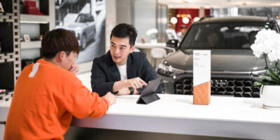two men looking at an ipad in car showroom